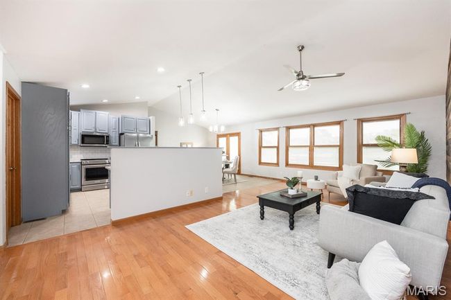 Living room with lofted ceiling, a ceiling fan, and light wood-style flooring | Image 12