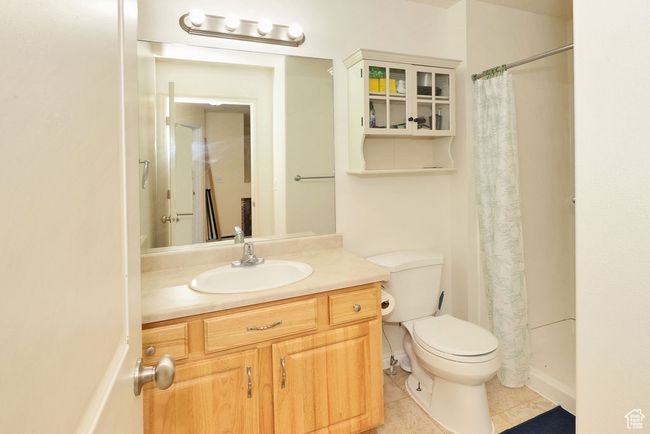 Bathroom featuring a shower with shower curtain, tile patterned flooring, vanity, and toilet | Image 23