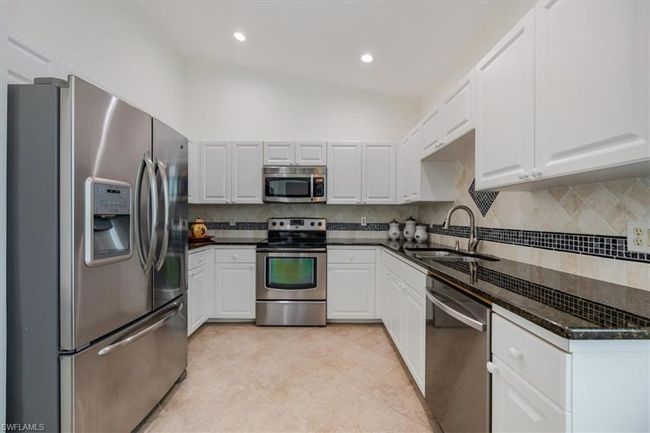 Kitchen with vaulted ceiling, backsplash, appliances with stainless steel finishes, sink, and white cabinets | Image 7