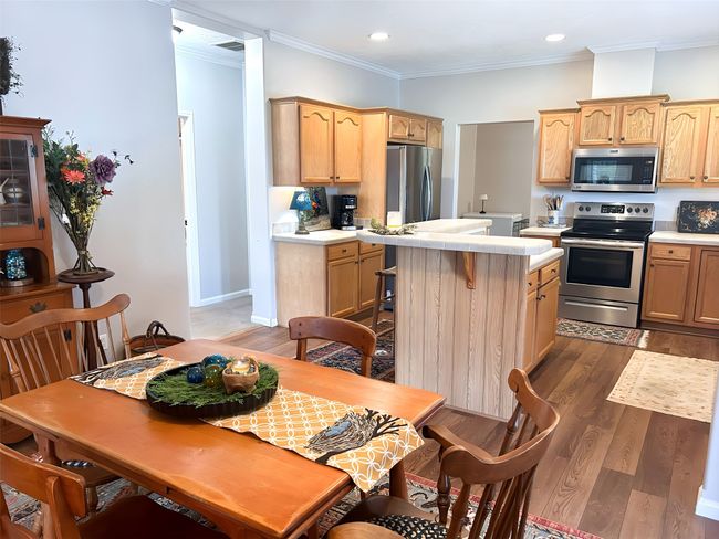 Kitchen with light countertops, a center island, appliances with stainless steel finishes, and dark wood-type flooring | Image 17