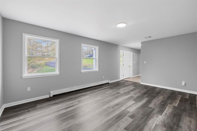 Empty room with baseboards, visible vents, wood finished floors, and a baseboard heating unit | Image 26