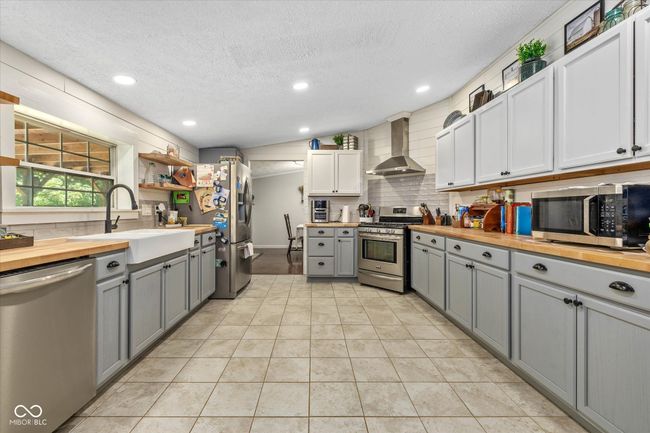 An updated farmhouse kitchen includes a farmhouse sink, shiplap and a tiled backsplash. | Image 6