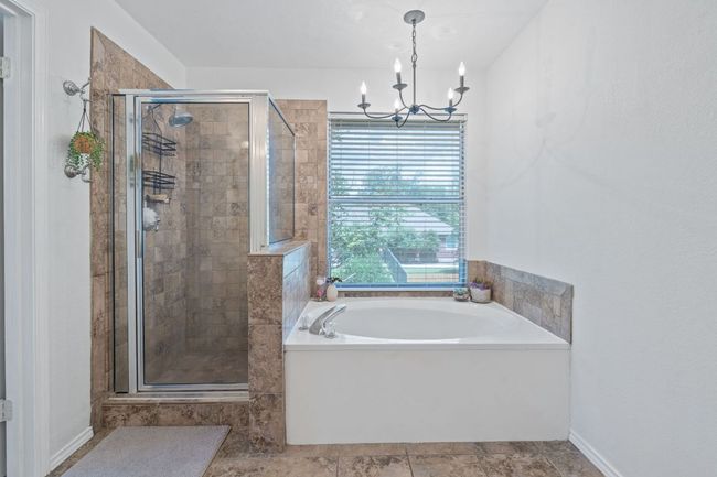 Bathroom featuring a garden tub, a stall shower, and a chandelier | Image 23