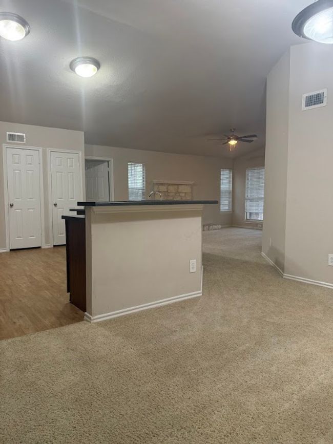 Kitchen with carpet floors, a ceiling fan, and a kitchen island with sink | Image 5