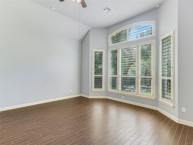 The primary bedroom is highlighted with a soaring ceiling, bay windows, plantation shutters, and a heavily wooded view for ultimate privacy. | Image 15