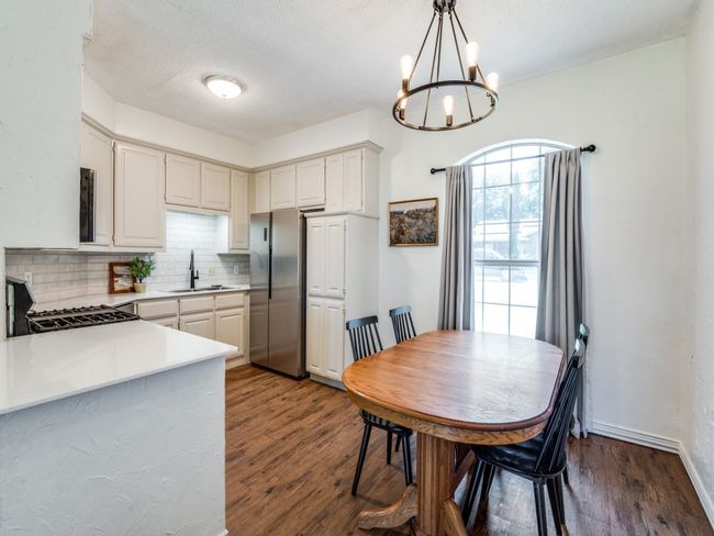 Kitchen featuring freestanding refrigerator, a chandelier, backsplash, dark wood-style flooring, and gas stove | Image 12