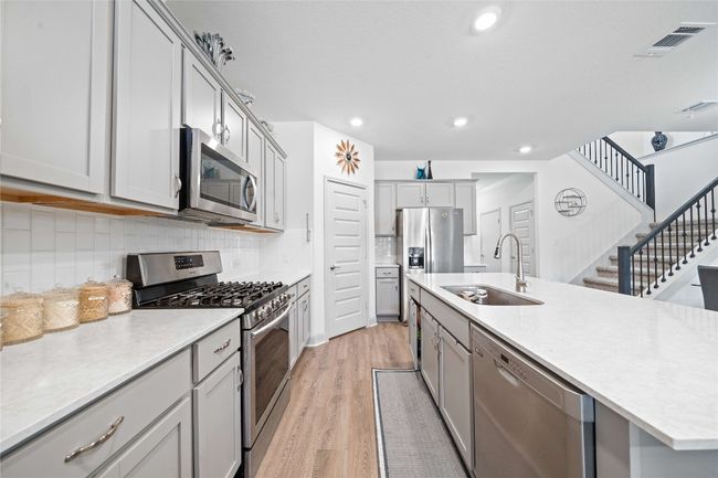 Kitchen with visible vents, a sink, light wood-type flooring, stainless steel appliances, and gray cabinets | Image 10