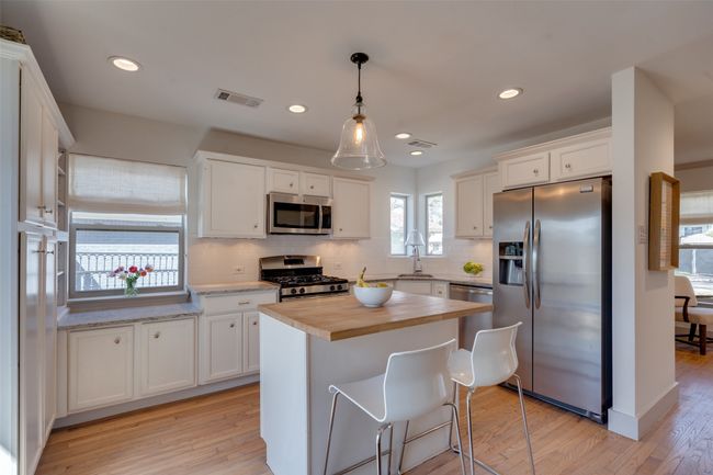 Kitchen with visible vents, appliances with stainless steel finishes, light wood-style flooring, and wood counters | Image 5