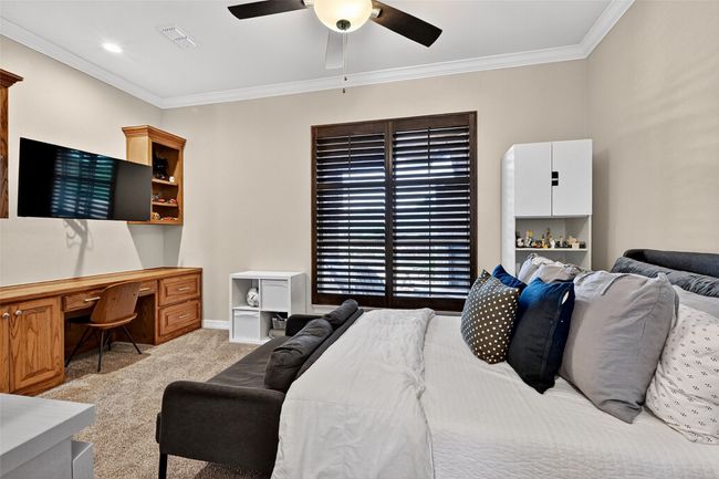 Bedroom featuring light colored carpet, ornamental molding, ceiling fan, and built in desk | Image 32