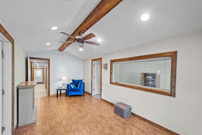Sitting room with light wood-style flooring, baseboards, ceiling fan, recessed lighting, and vaulted ceiling with beams | Image 32