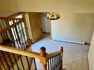 Staircase featuring an inviting chandelier, tile patterned floors, and a baseboard heating unit | Image 3