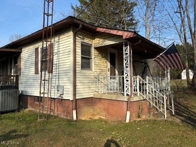 View of property exterior with central AC unit, a porch, and a lawn | Image 3