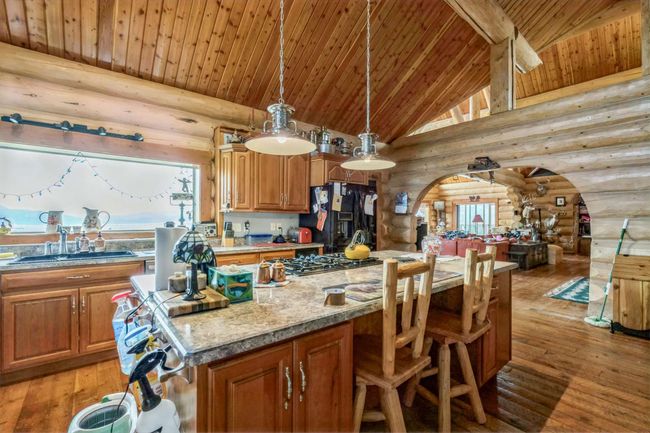 Kitchen featuring rustic walls, arched walkways, wooden ceiling with exposed beams, black fridge, and a sink | Image 31