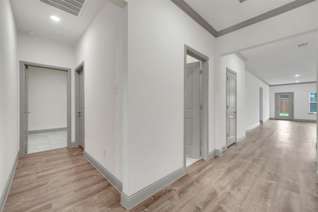Hall featuring light wood-style floors, visible vents, baseboards, and crown molding | Image 7