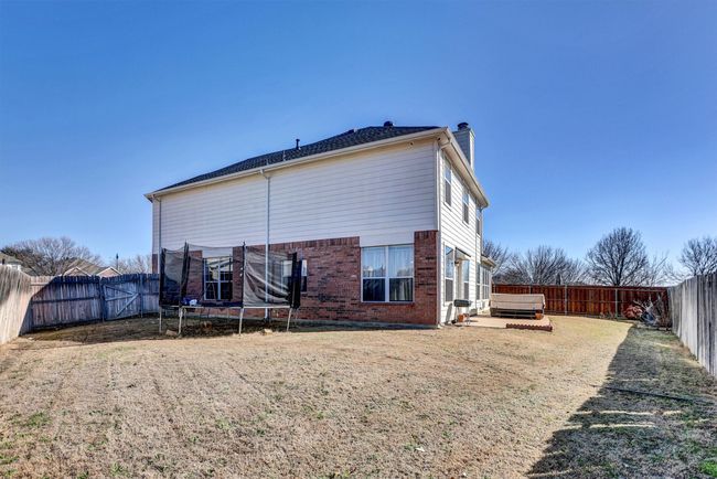 Back of property with brick siding, a chimney, a fenced backyard, and a jacuzzi | Image 5