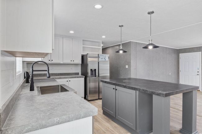 Kitchen featuring stainless steel refrigerator with ice dispenser, open shelves, light wood-style floors, dark countertops, and a center island | Image 19