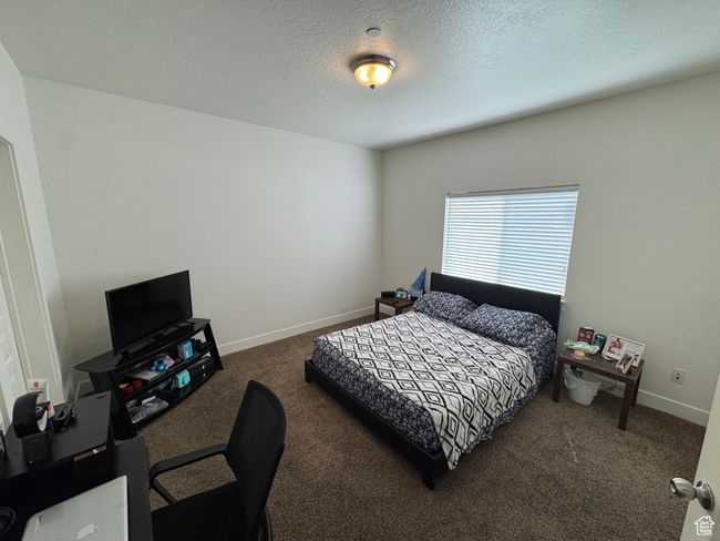 Bedroom with a textured ceiling, baseboards, and carpet | Image 8
