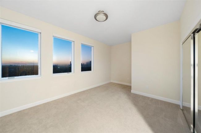 The secondary bedroom is spacious with multiple windows plus a large clothes closet with mirrored sliding doors on the right. | Image 28
