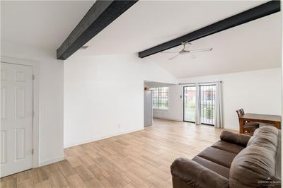 Living room featuring light hardwood / wood-style floors, vaulted ceiling with beams, and ceiling fan | Image 2