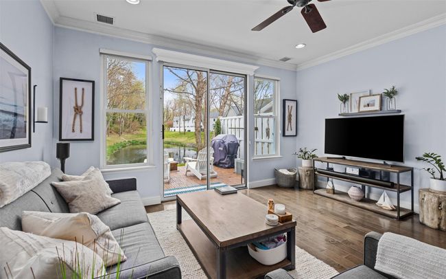 Living area featuring baseboards, visible vents, a ceiling fan, wood finished floors, and crown molding | Image 7