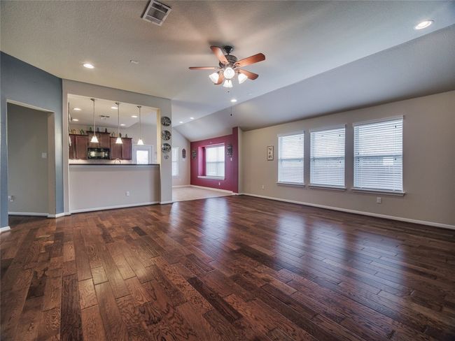 Unfurnished living room with dark wood finished floors, ceiling fan, baseboards, and vaulted ceiling | Image 22
