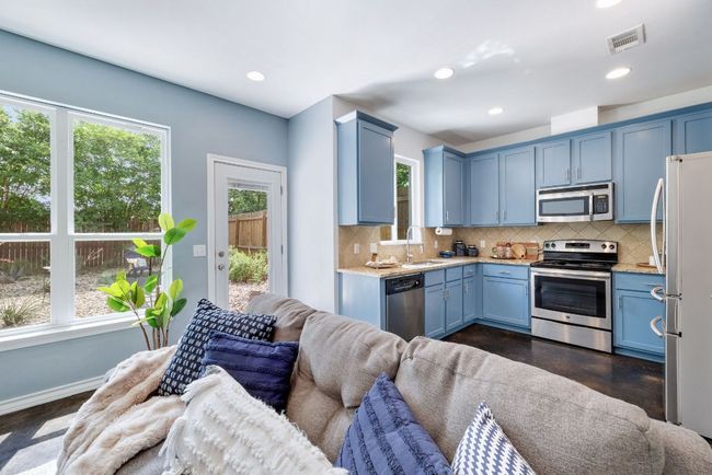 Kitchen featuring stainless steel appliances, open floor plan, a sink, blue cabinetry, and decorative backsplash | Image 14