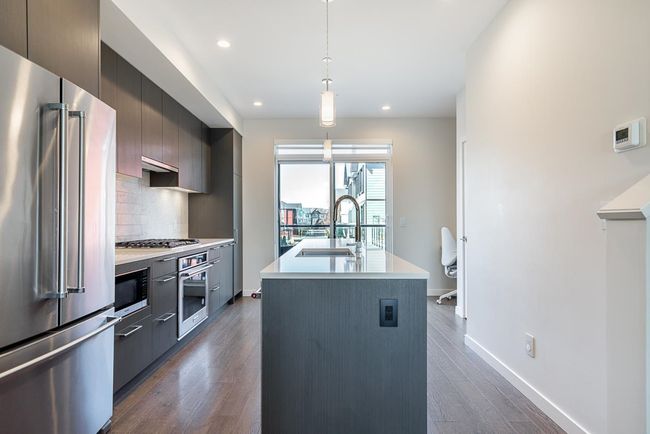 Kitchen featuring a sink, stainless steel appliances, light countertops, modern cabinets, and backsplash | Image 9