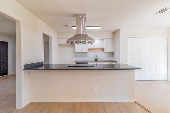 Kitchen featuring tasteful backsplash, light wood finished floors, white cabinetry, and a sink | Image 7