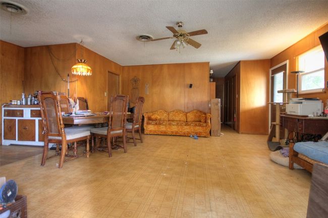 Dining space with wooden walls, ceiling fan, a textured ceiling, and tile patterned floors | Image 5