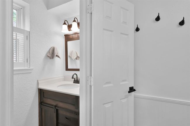A Half-Bath is located off the Kitchen and Laundry Room with an oil-rubbed bronze faucet, updated light fixture and framed mirror. | Image 24
