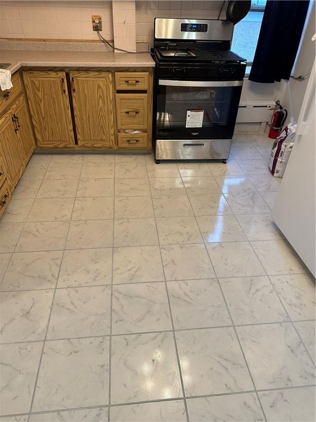 Kitchen with backsplash, range, and light tile patterned floors | Image 5
