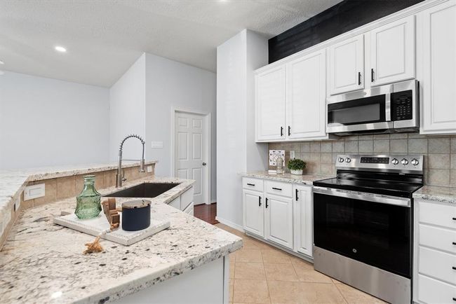 The kitchen has been tastefully updated with freshly painted white cabinetry, granite countertops and stainless appliances. | Image 11