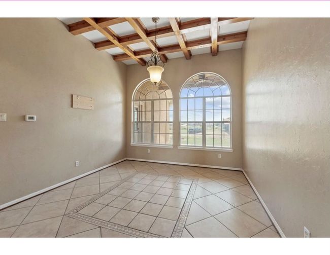 Unfurnished room with beam ceiling, light tile patterned floors, coffered ceiling, and inlaid floor details | Image 5