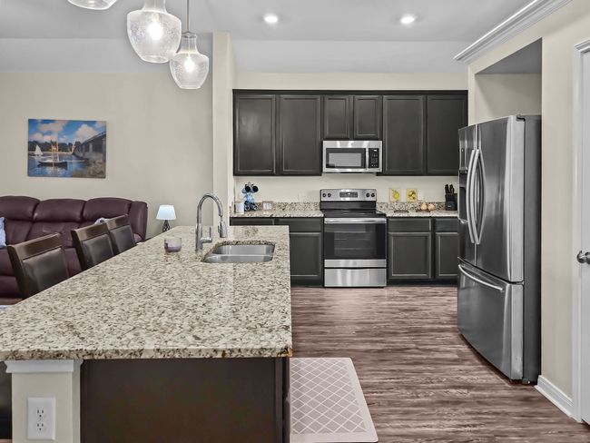 Kitchen with appliances with stainless steel finishes, dark wood-style flooring, light stone countertops, open floor plan, and recessed lighting | Image 4