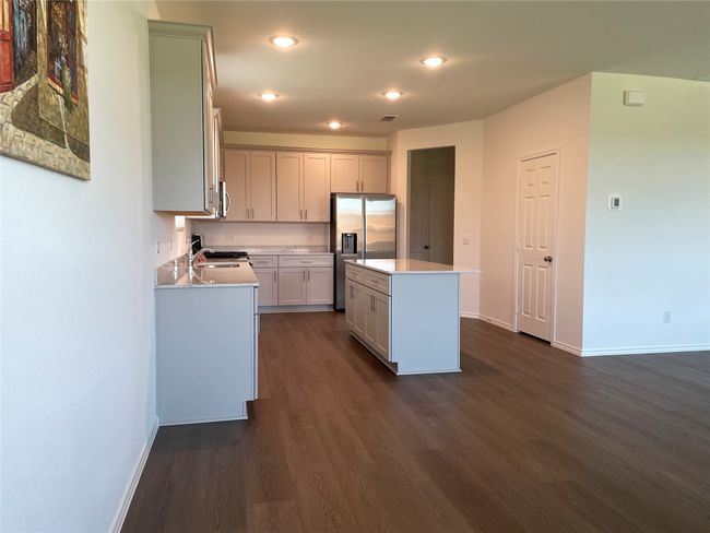 Kitchen featuring stainless steel appliances, baseboards, dark wood-type flooring, a kitchen island, and light countertops | Image 7