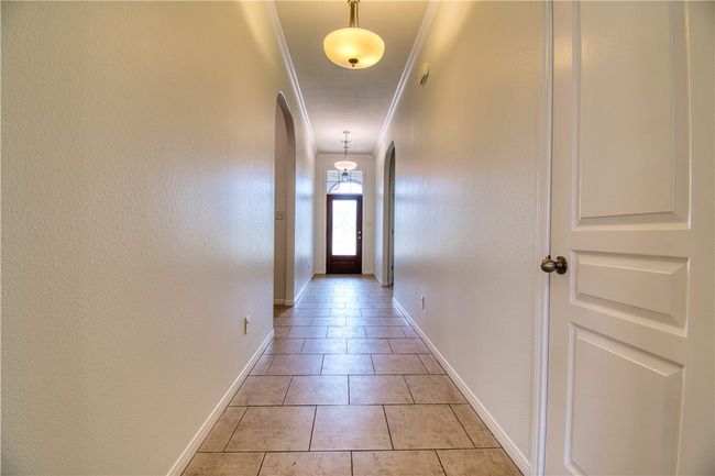 Corridor with arched walkways, ornamental molding, baseboards, and light tile patterned floors | Image 9