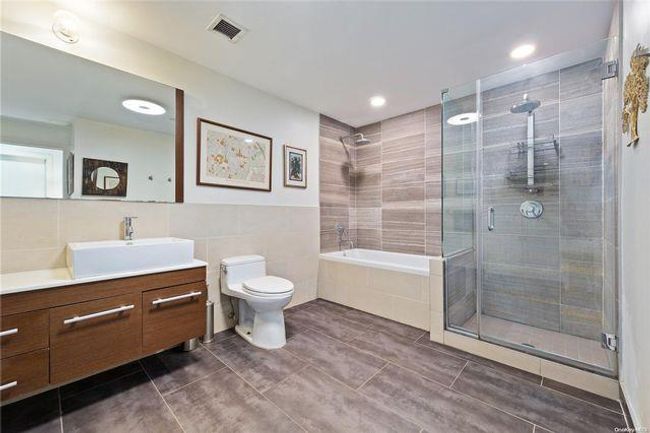 Full bathroom with tile patterned flooring, tile walls, toilet, vanity, and plus walk in shower | Image 10