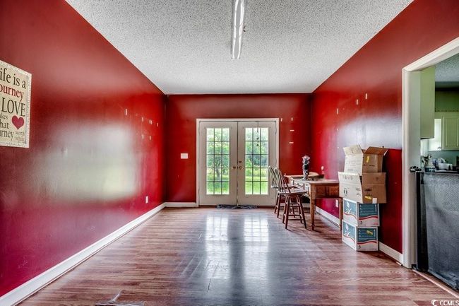 Doorway to outside with wood finished floors, a textured ceiling, french doors, and baseboards | Image 15