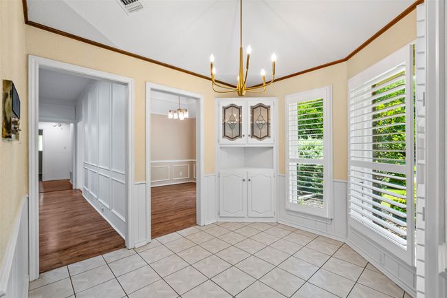 Unfurnished dining area with a chandelier, ornamental molding, light tile patterned floors, a decorative wall, and a wainscoted wall | Image 9