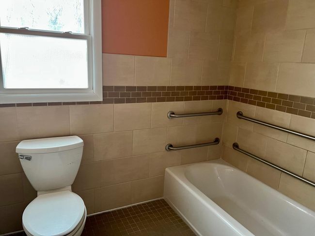 Full bathroom featuring tile walls, toilet, a washtub, and tile patterned flooring | Image 20