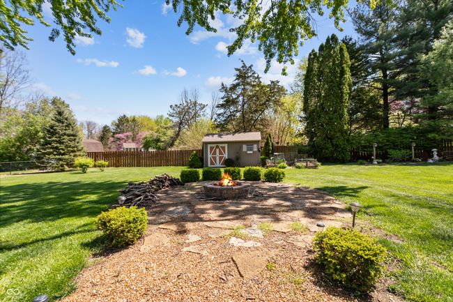 view of yard featuring a fire pit, an outbuilding, a fenced backyard, and a storage shed | Image 39
