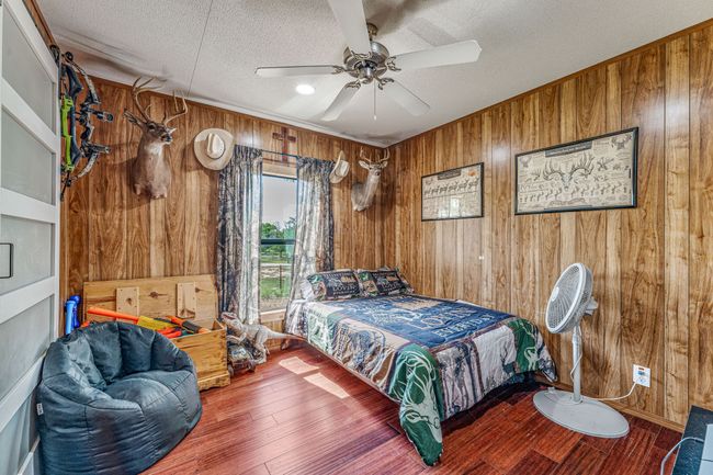Bedroom featuring wood finished floors, a textured ceiling, wood walls, and ceiling fan | Image 20