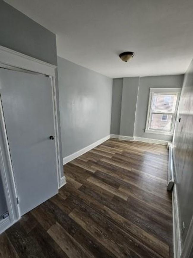 Unfurnished bedroom featuring dark wood-style flooring and baseboards | Image 6