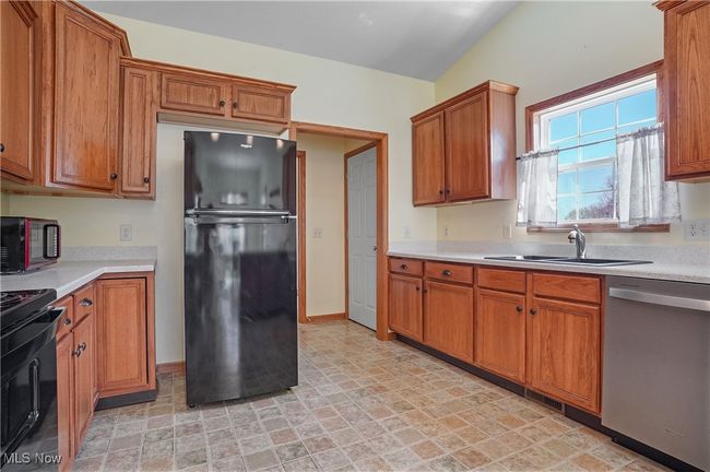 Kitchen featuring stainless steel dishwasher, a sink, range, light countertops, and freestanding refrigerator | Image 20