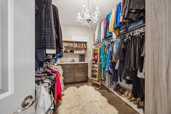 Spacious walk-in closet featuring ample hanging space, built-in drawers, and a luxurious chandelier. Perfect for organizing a large wardrobe. This is one of the two primary closets. | Image 22