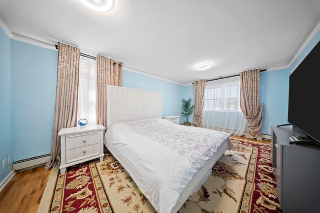 Bedroom featuring a baseboard radiator, wood finished floors, and ornamental molding | Image 13