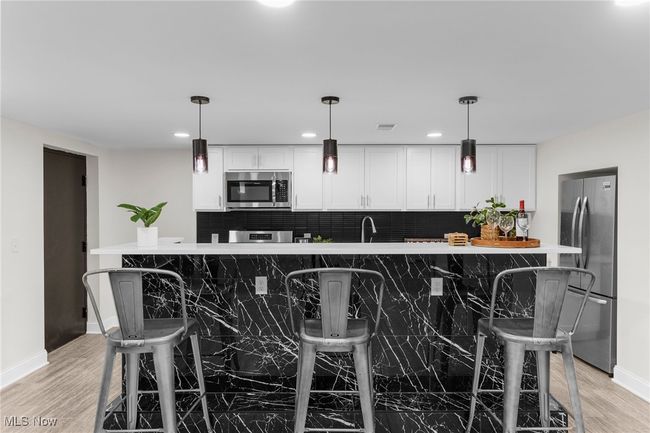 Kitchen with appliances with stainless steel finishes, tasteful backsplash, white cabinetry, light wood-type flooring, and recessed lighting | Image 31