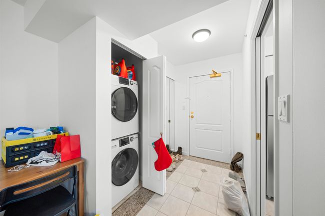 Washroom featuring stacked washer / drying machine, laundry area, and light tile patterned floors | Image 16