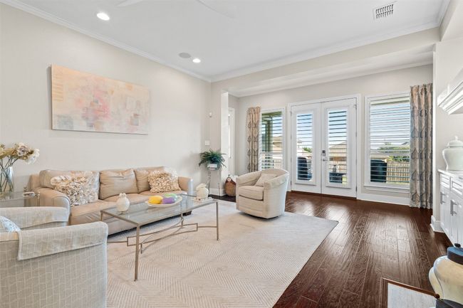 This spacious living room is adorned with rich engineered wood flooring and custom built-ins that offer both style and storage. | Image 12