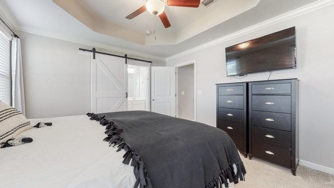 Primary bedroom with tray ceiling and barn door to bathroom | Image 13